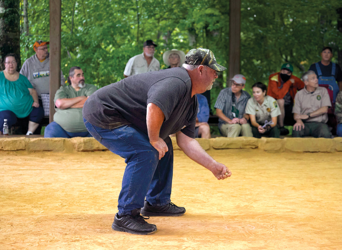 A man plays in the 2021 National Rolley Hole Championships while a small crowd watches.