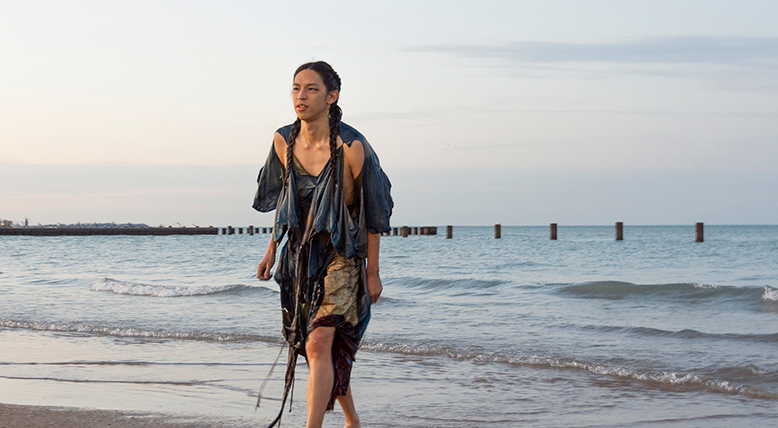 Artist Hai-Wen Lin emerging from Lake Michigan wearing a garment that can also be used as a kite