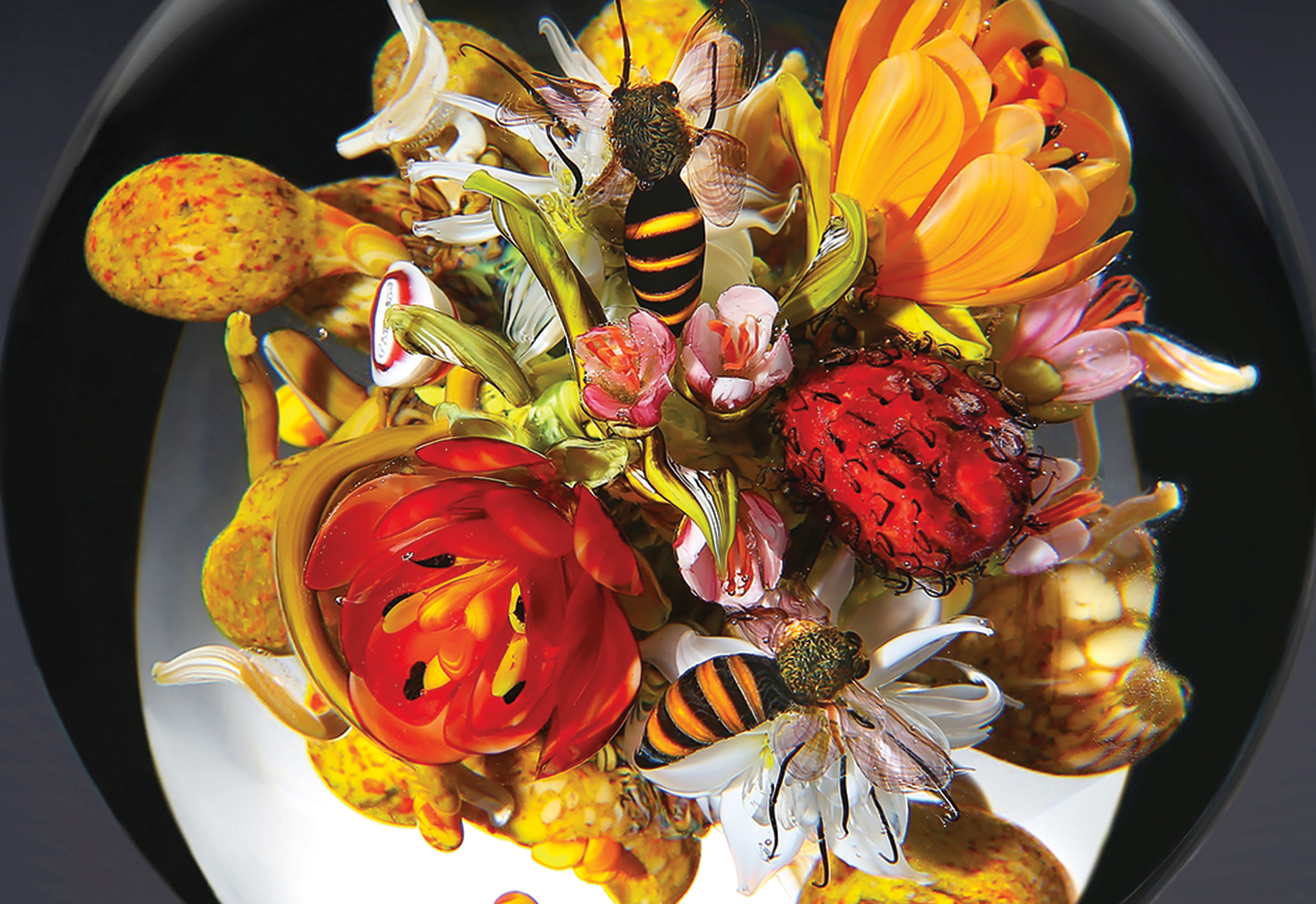 Detail from an intricate glass paperweight with interior flowers, fruit, and bees