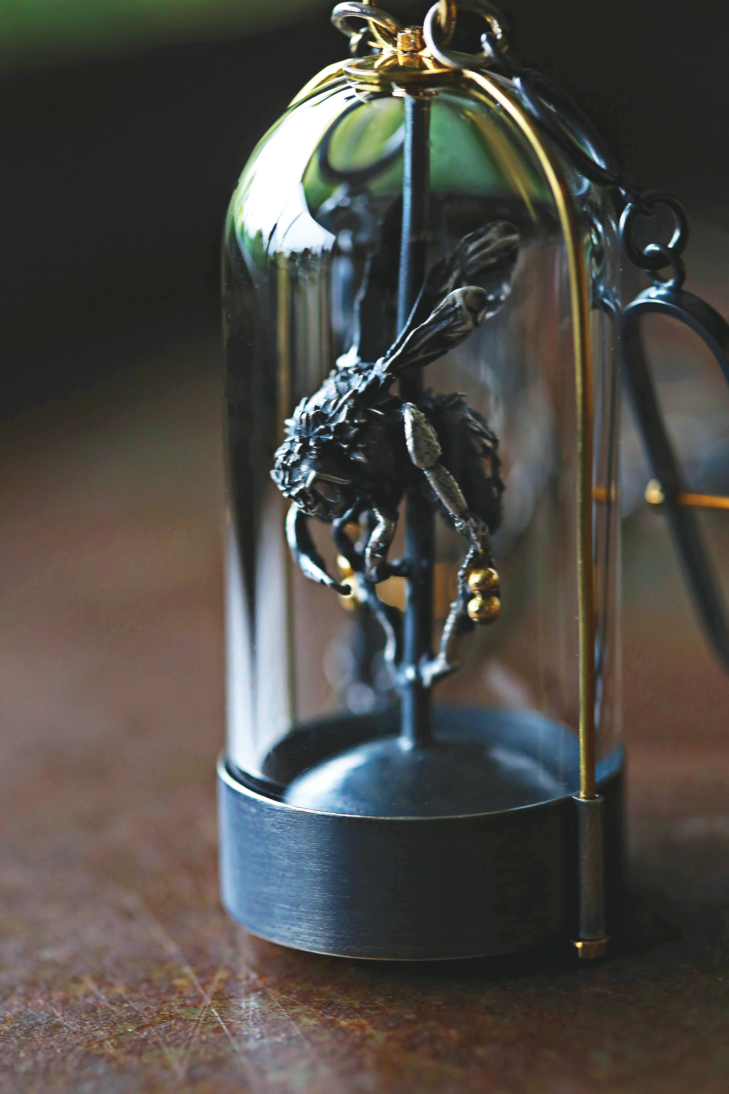 Necklace featuring a bumblebee cast in sterling silver inside a glass dome