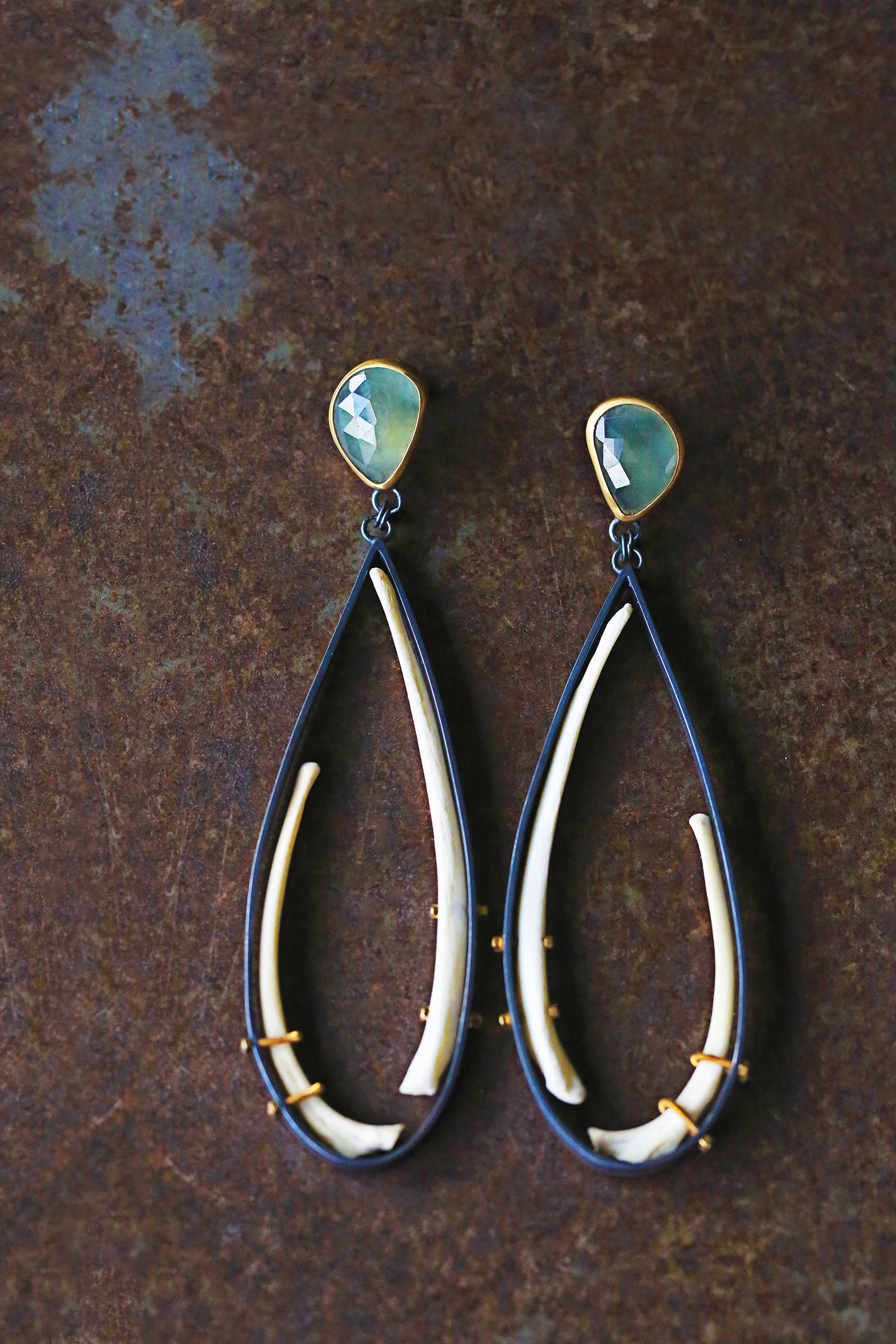 Earrings made from bobcat ribs, sapphire, 23k gold, sterling silver, and gold-plated bolts.