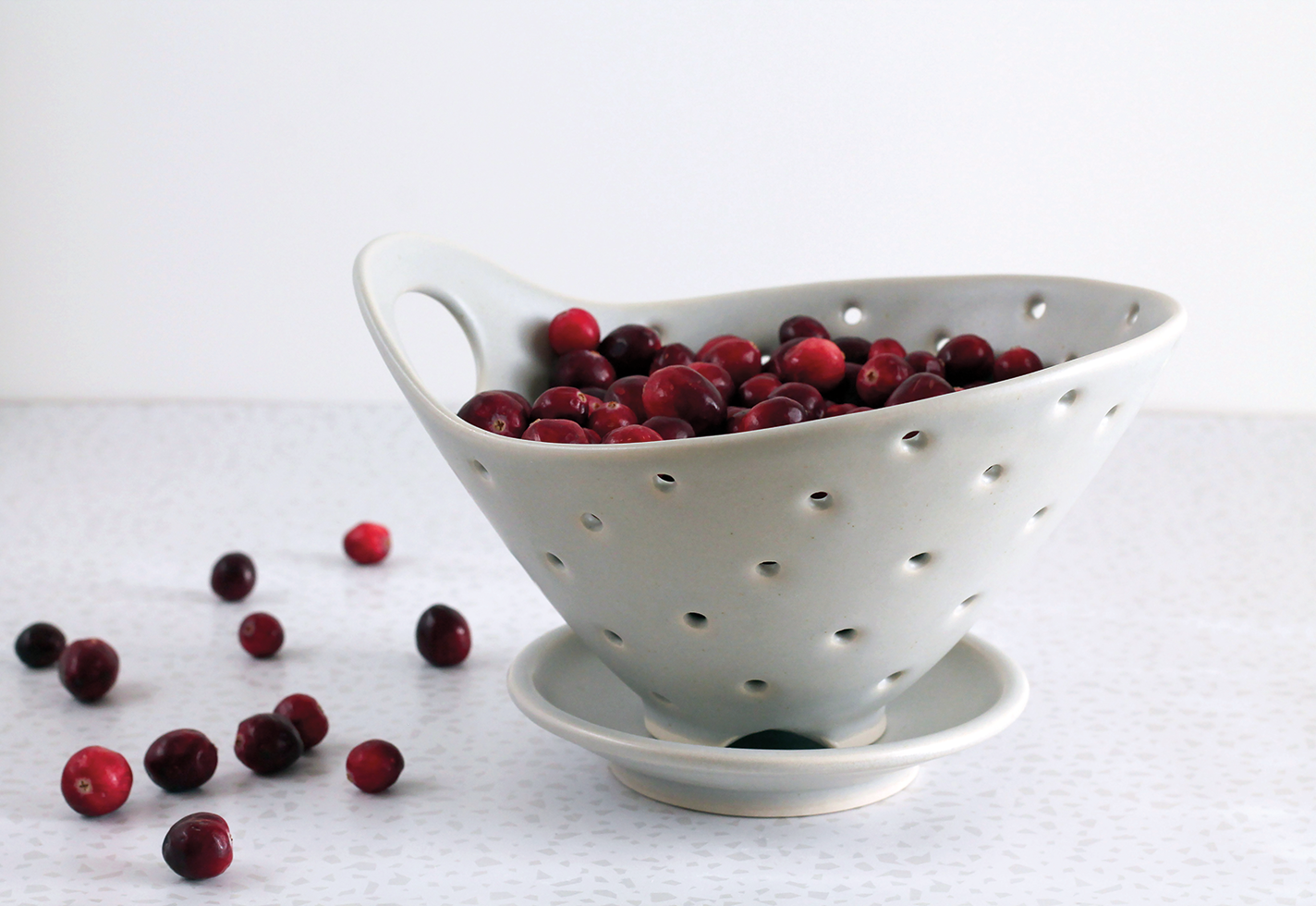 Small porcelain berry bowl with a handle and holes for rinsing