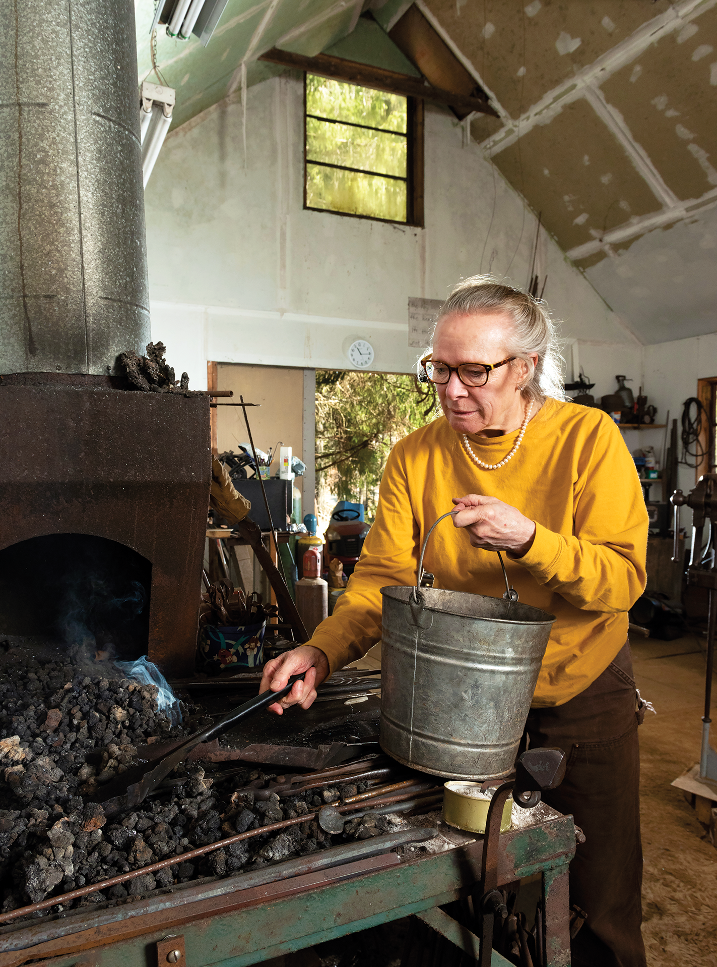 Elizabeth Brim adds coal to her forge fire.