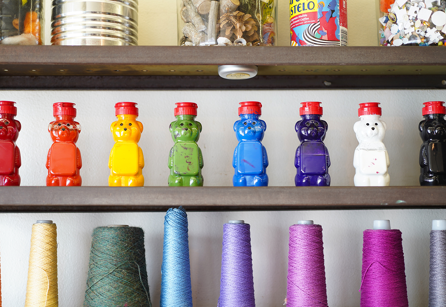 Honey bears filled with paint populate a supply shelf.