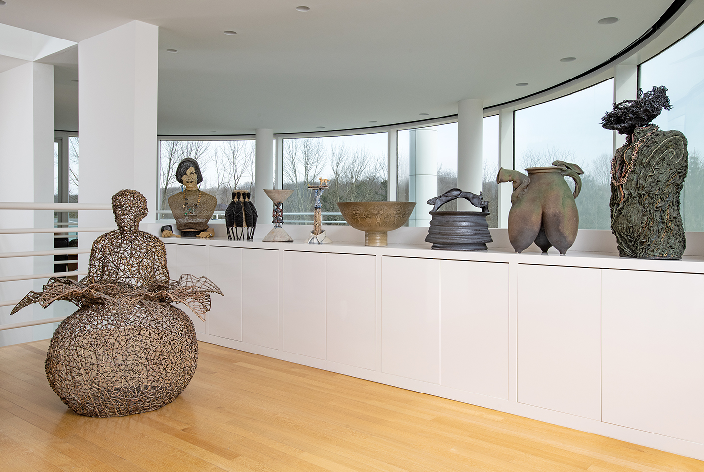Ceramics arranged on top of cabinets and a sculpture on the floor.