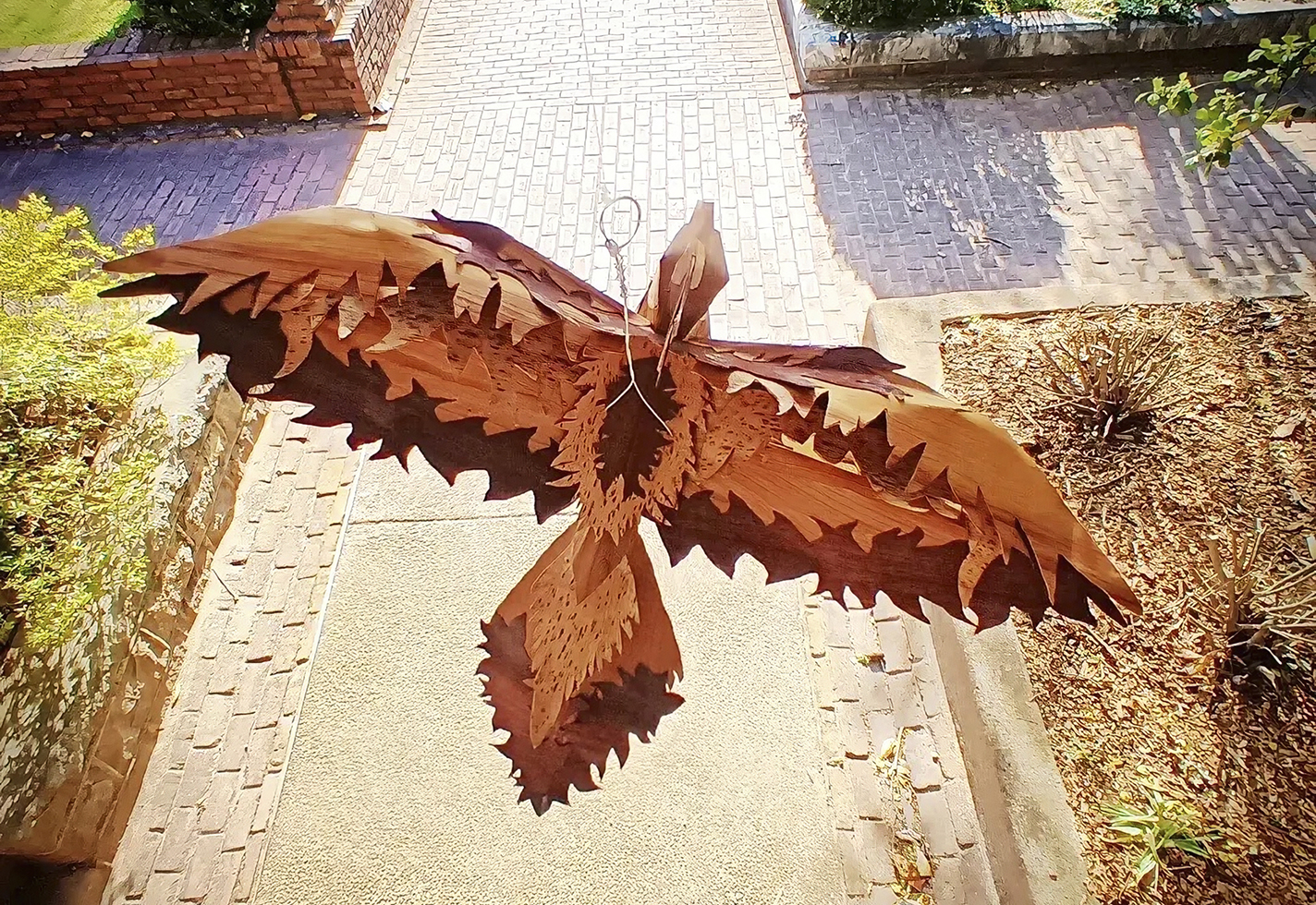 Wooden bird sculpture hanging from a tree