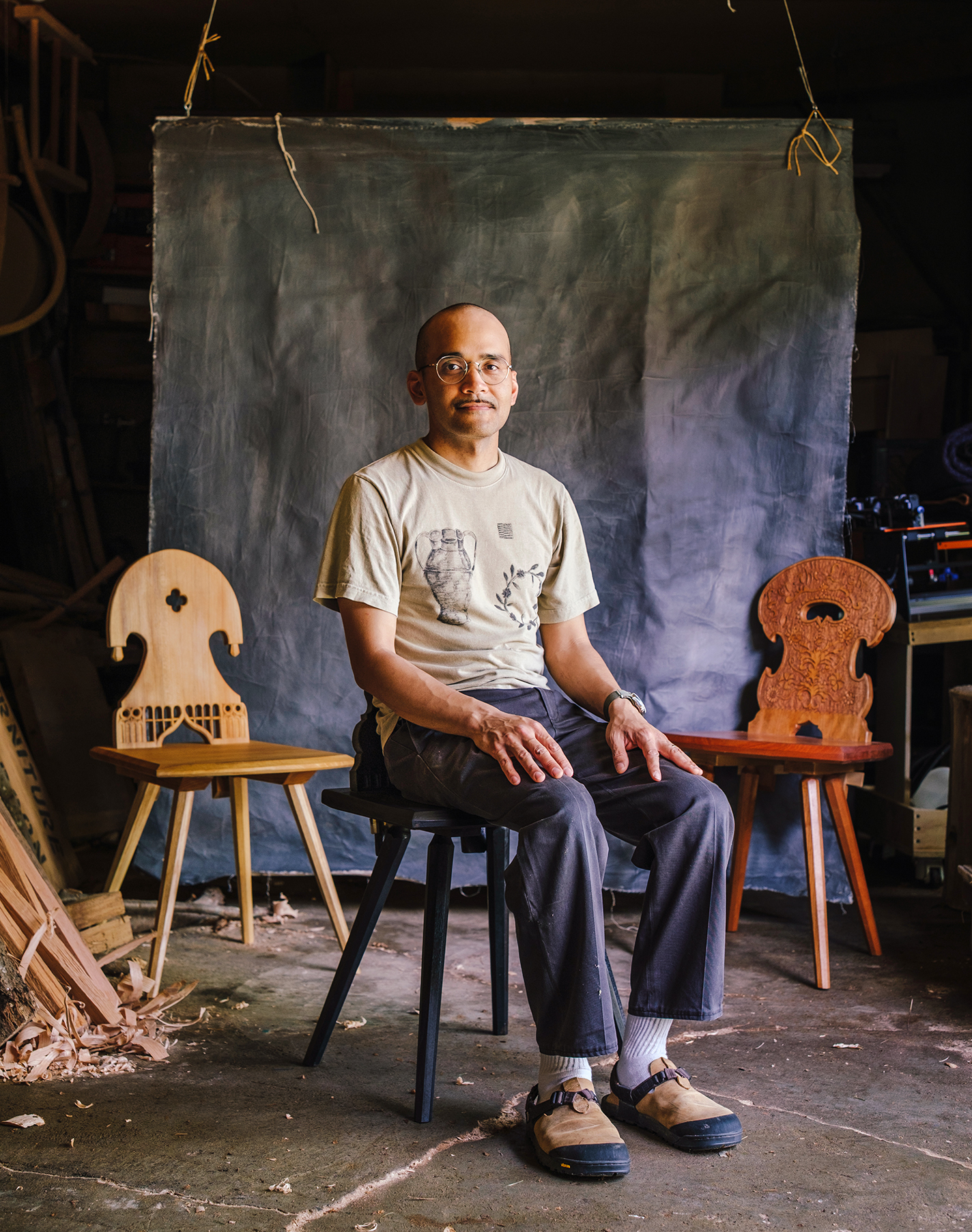 Charles Thompson sits on a wooden stool.
