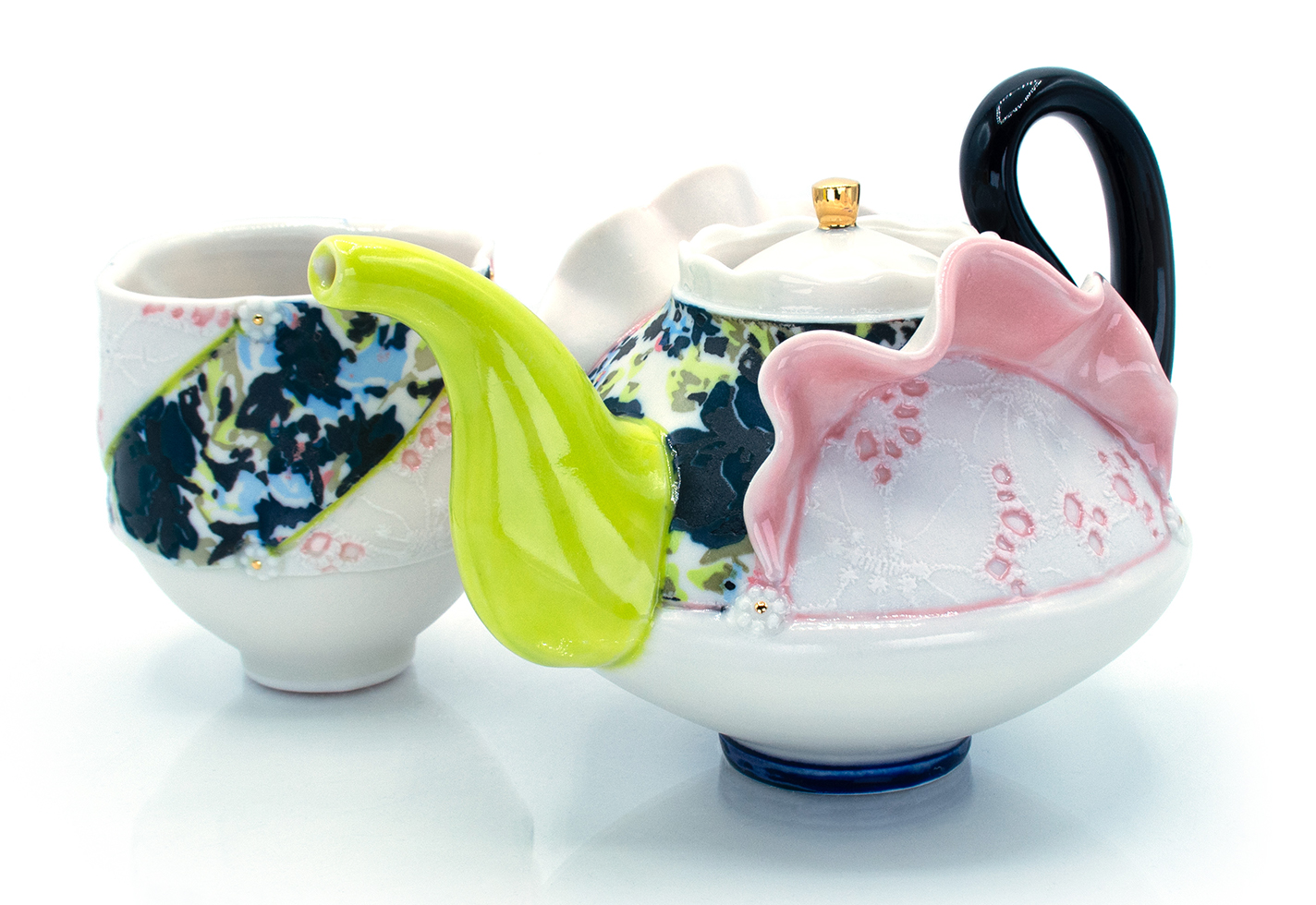 Floral-print ceramic teapot and teacup with lace inserts.