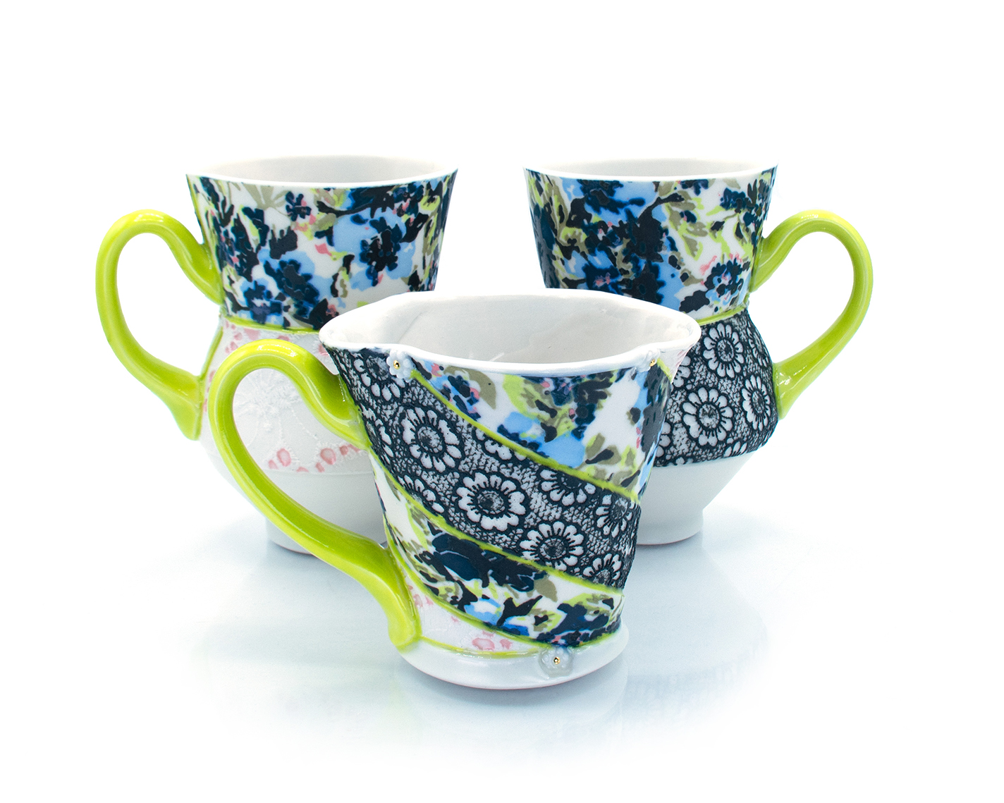 Three mugs with floral patterns and lace inserts.