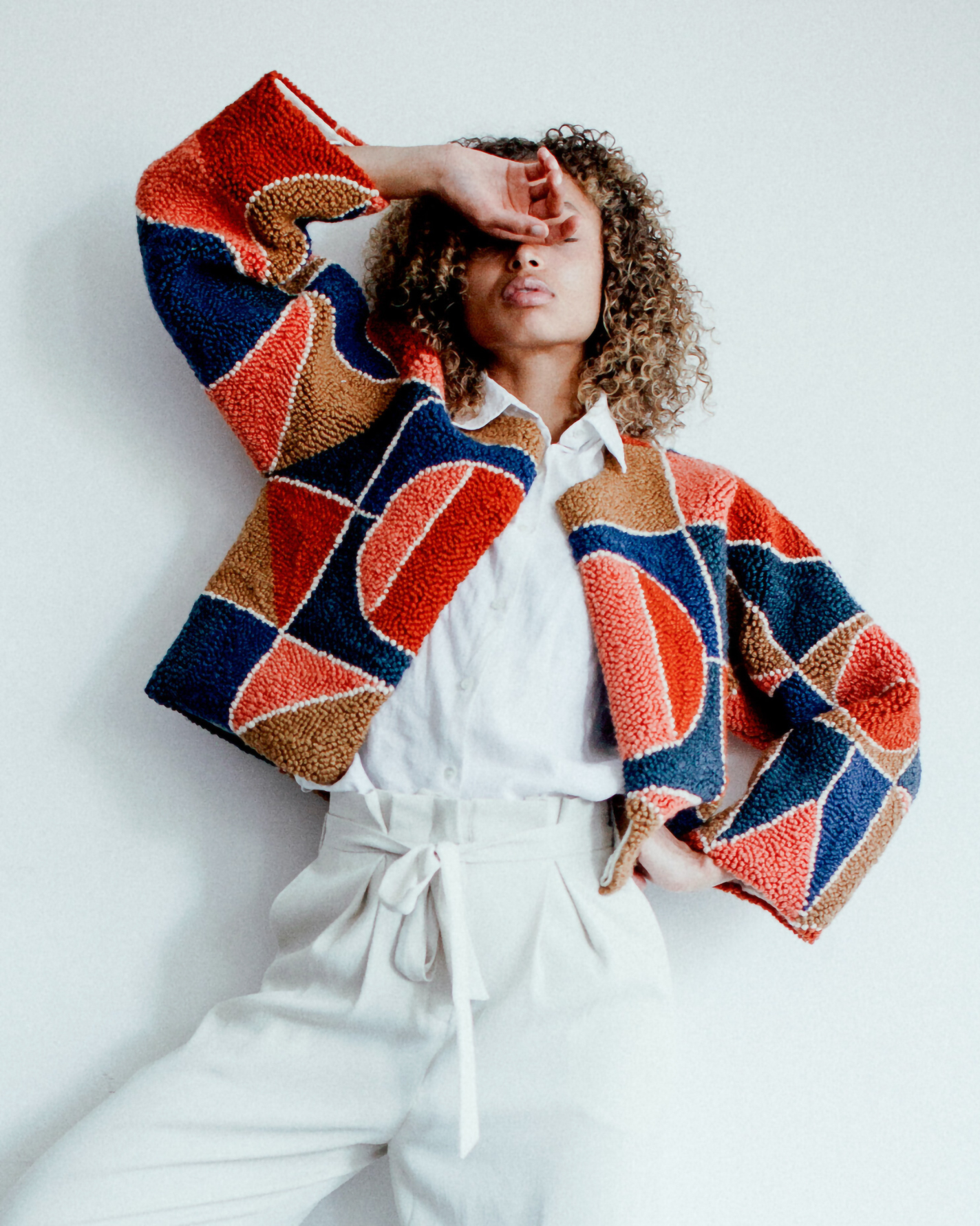 Cropped punch needle coat with midnight blue, coral, and brown shapes.