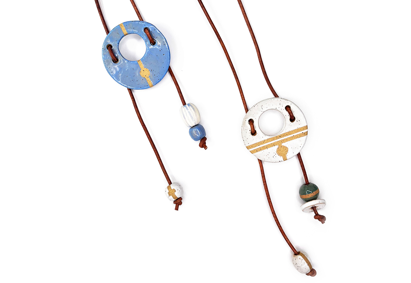 Two bolo ties: ceramic pendants on leather cords.