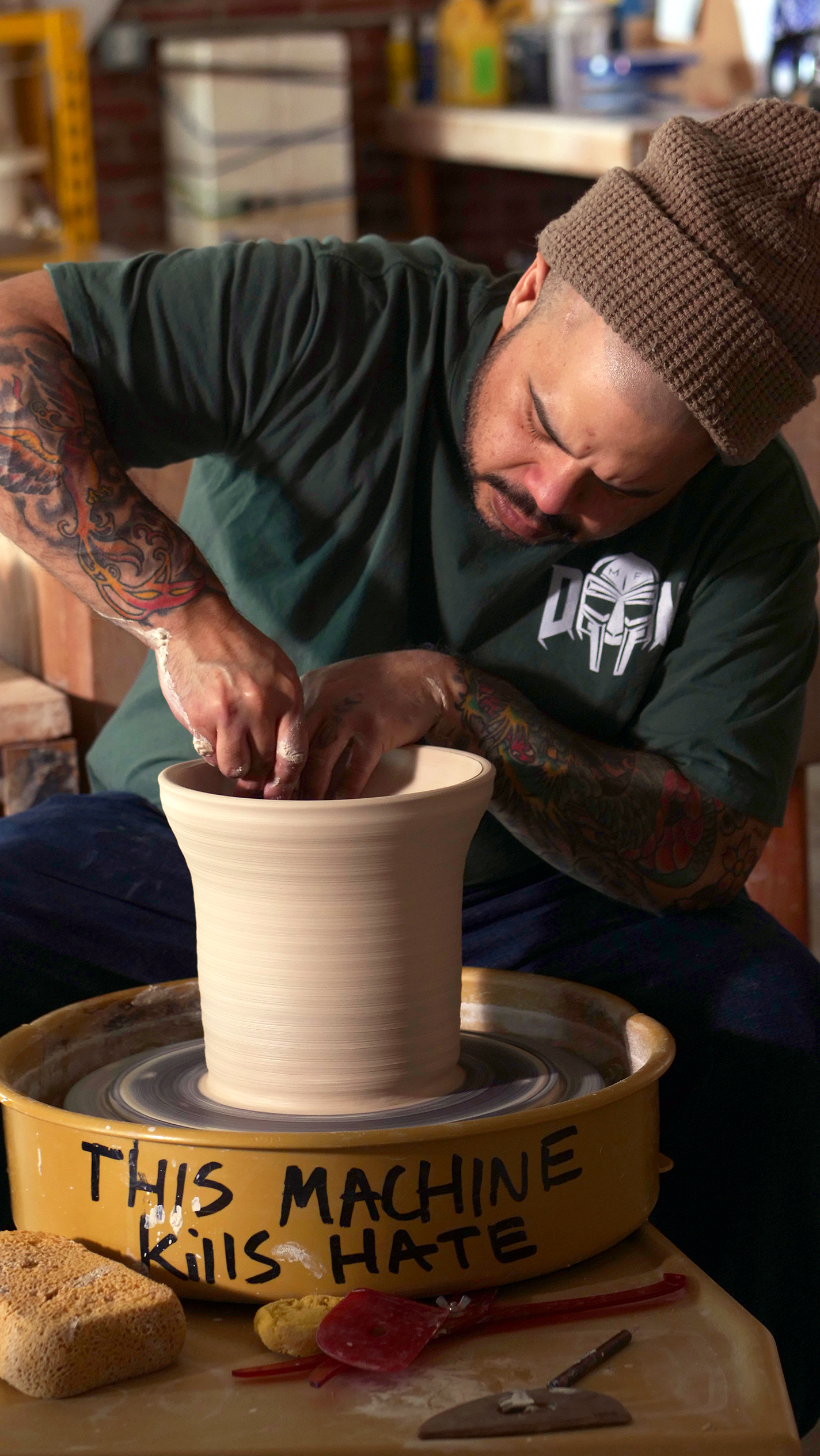 Potter Roberto Lugo throws a vessel on a pottery wheel marked with the words